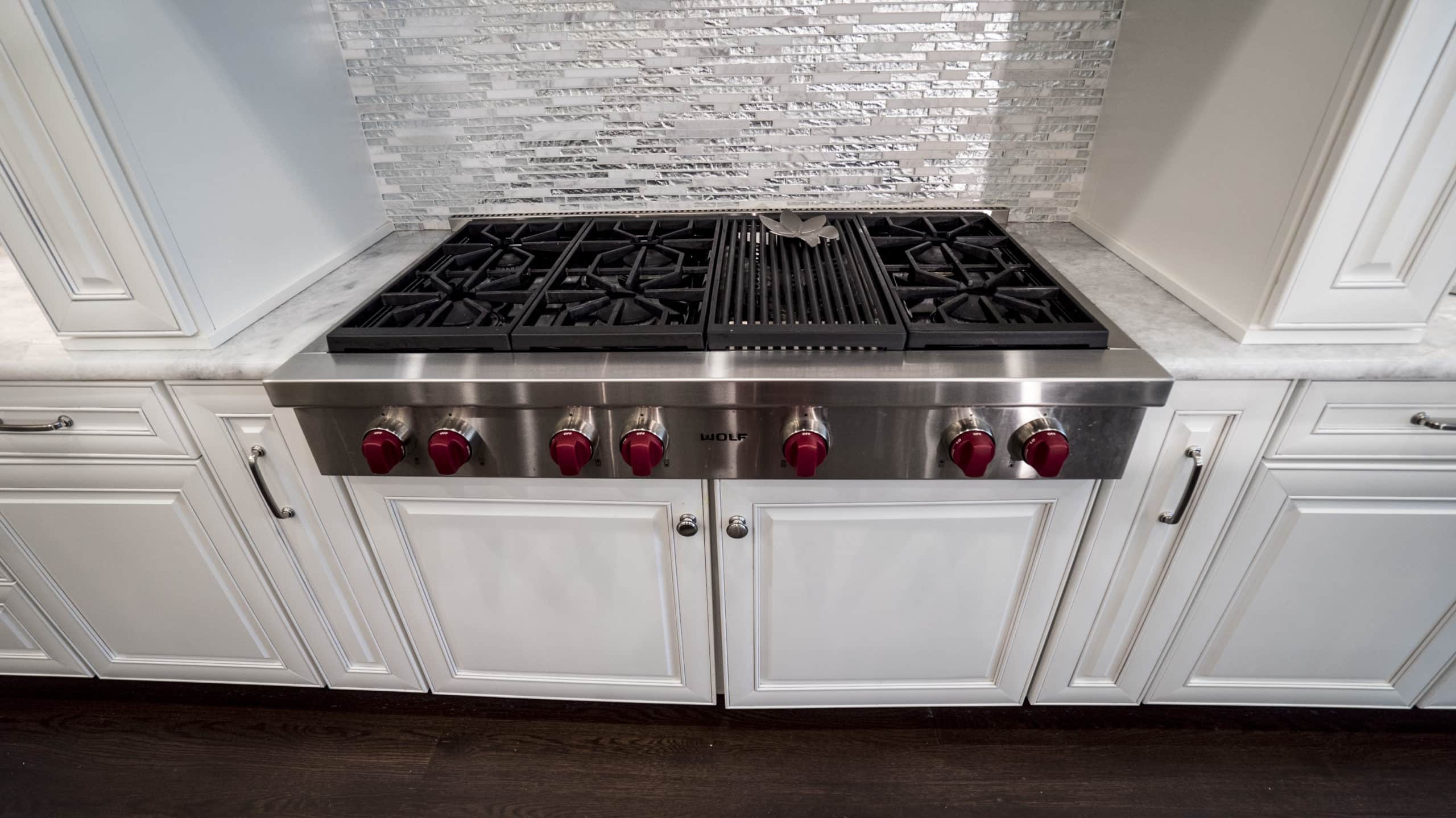A stainless steel stove top in a white kitchen