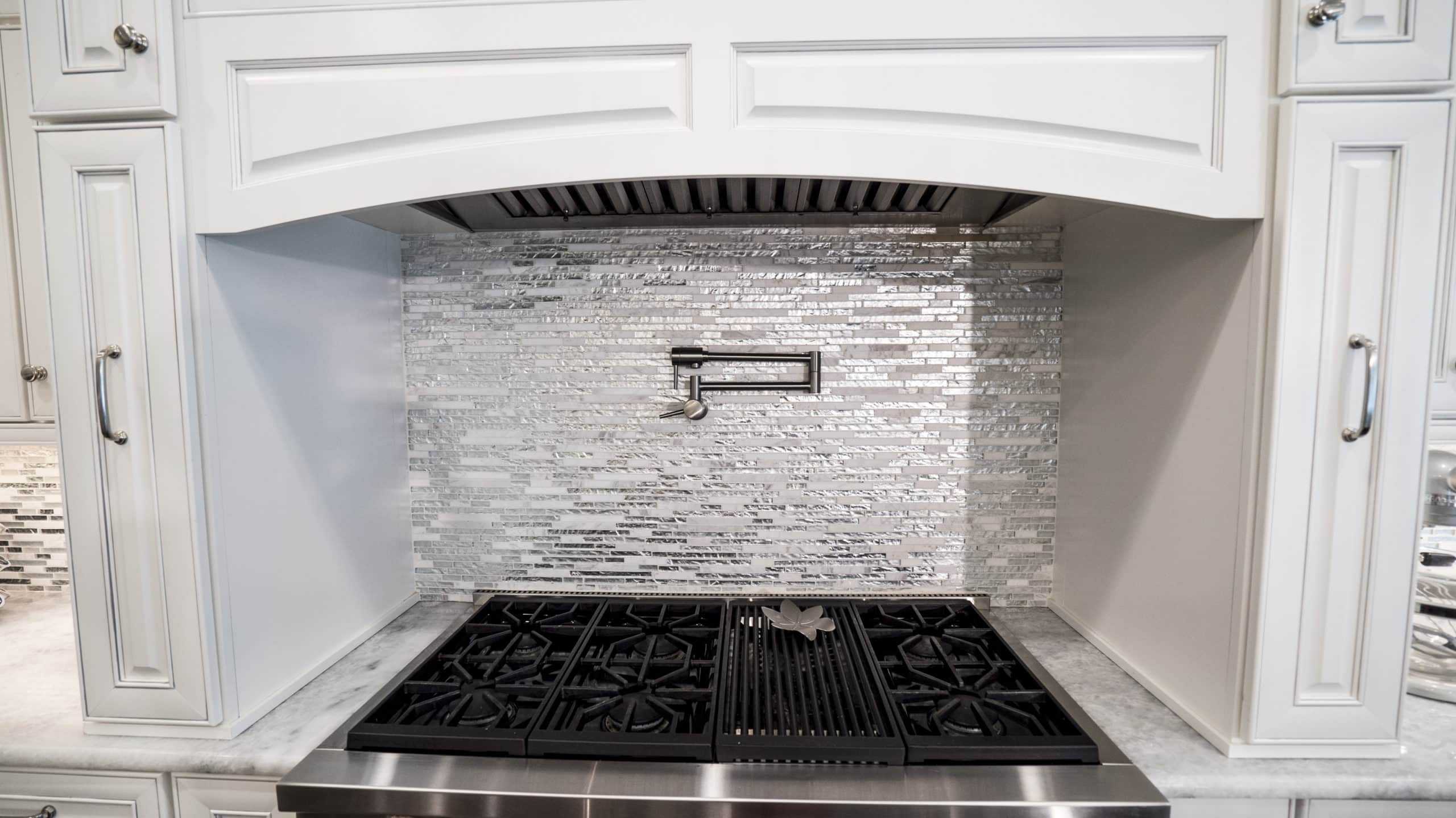 A stainless steel stove in a kitchen with white cabinets