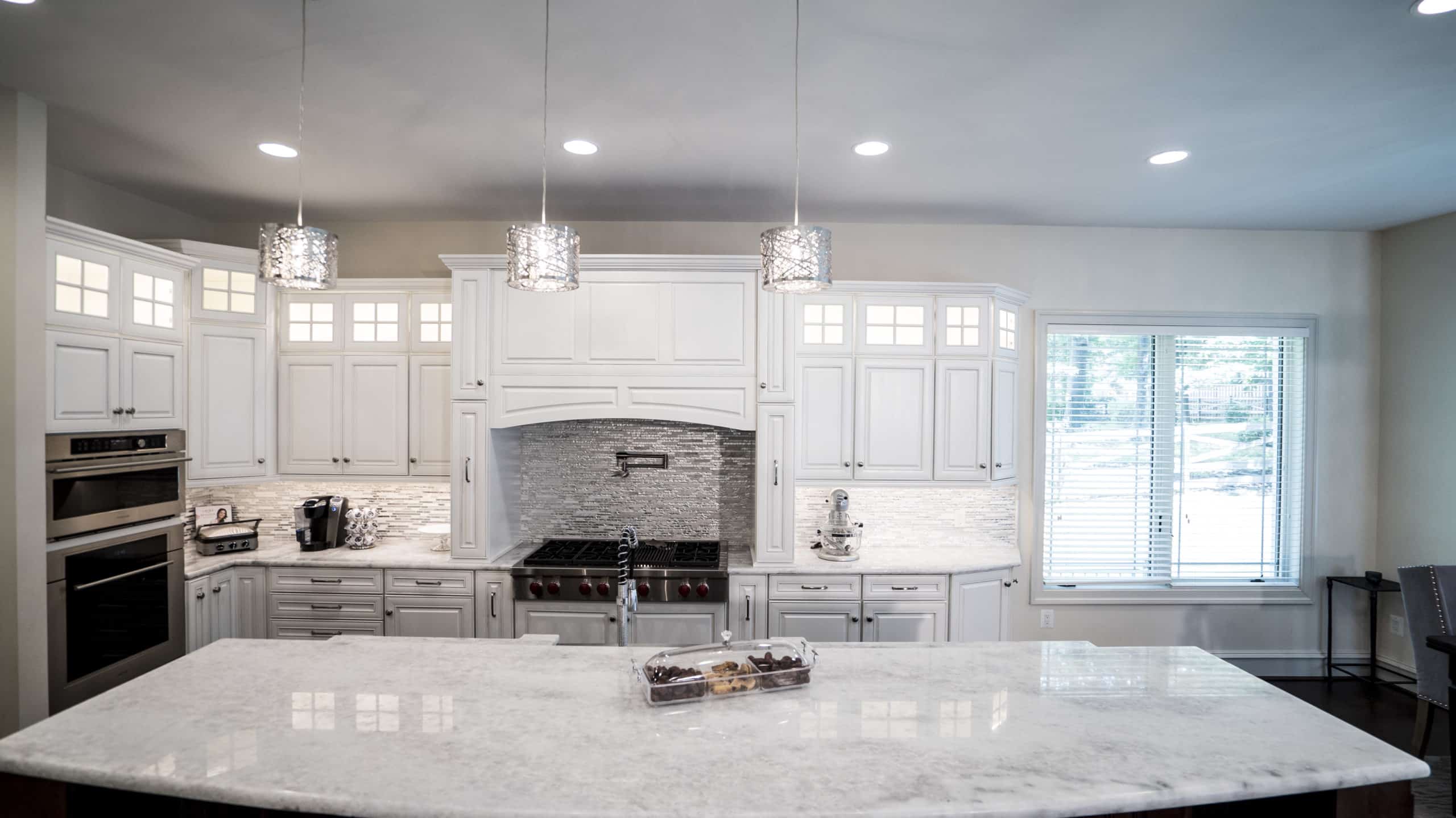 A kitchen with white cabinets and marble countertops