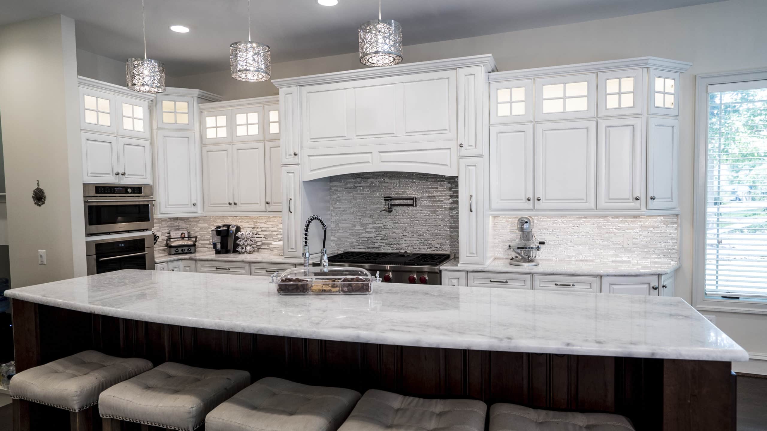 A kitchen with white cabinets and a marble island, creating a sleek and elegant design