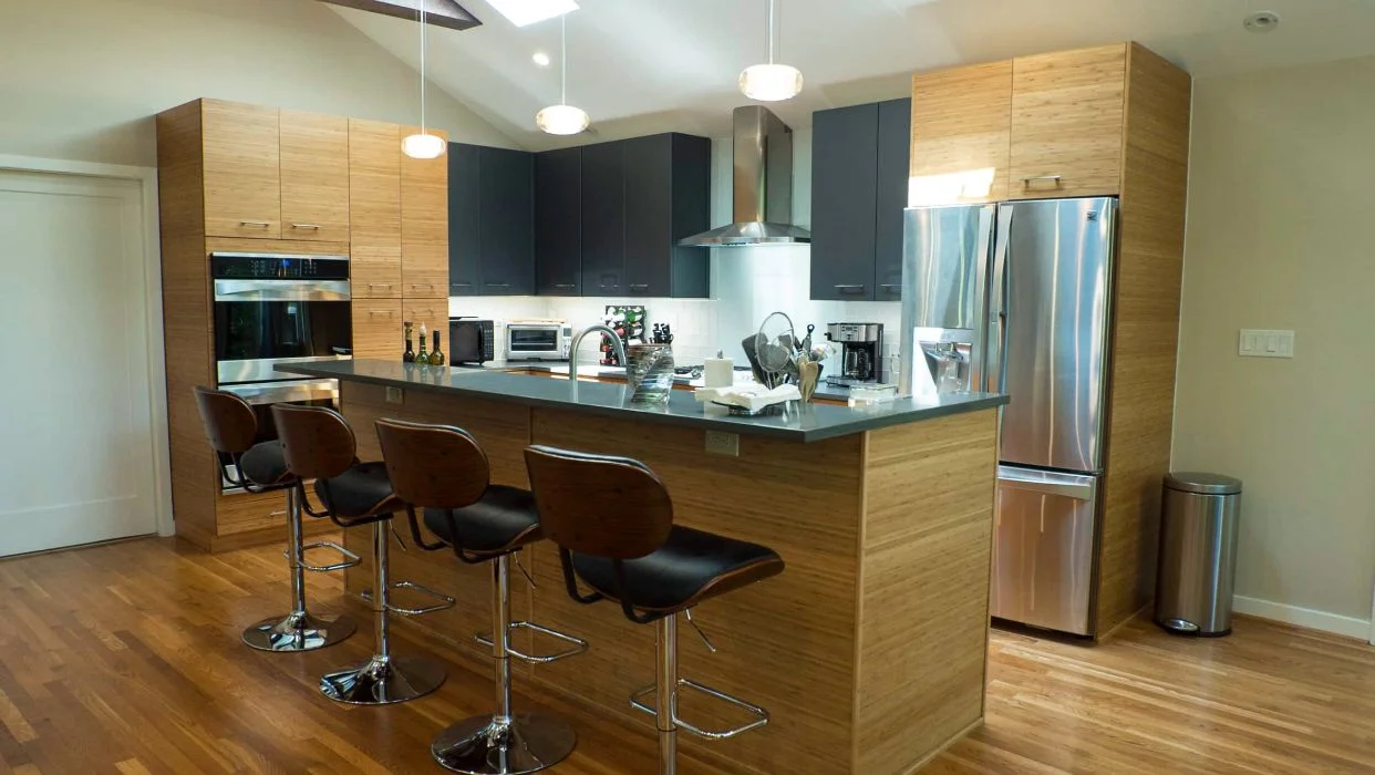 Modern kitchen with bamboo slab cabinets, dark wall cabinetry, and a large island with seating