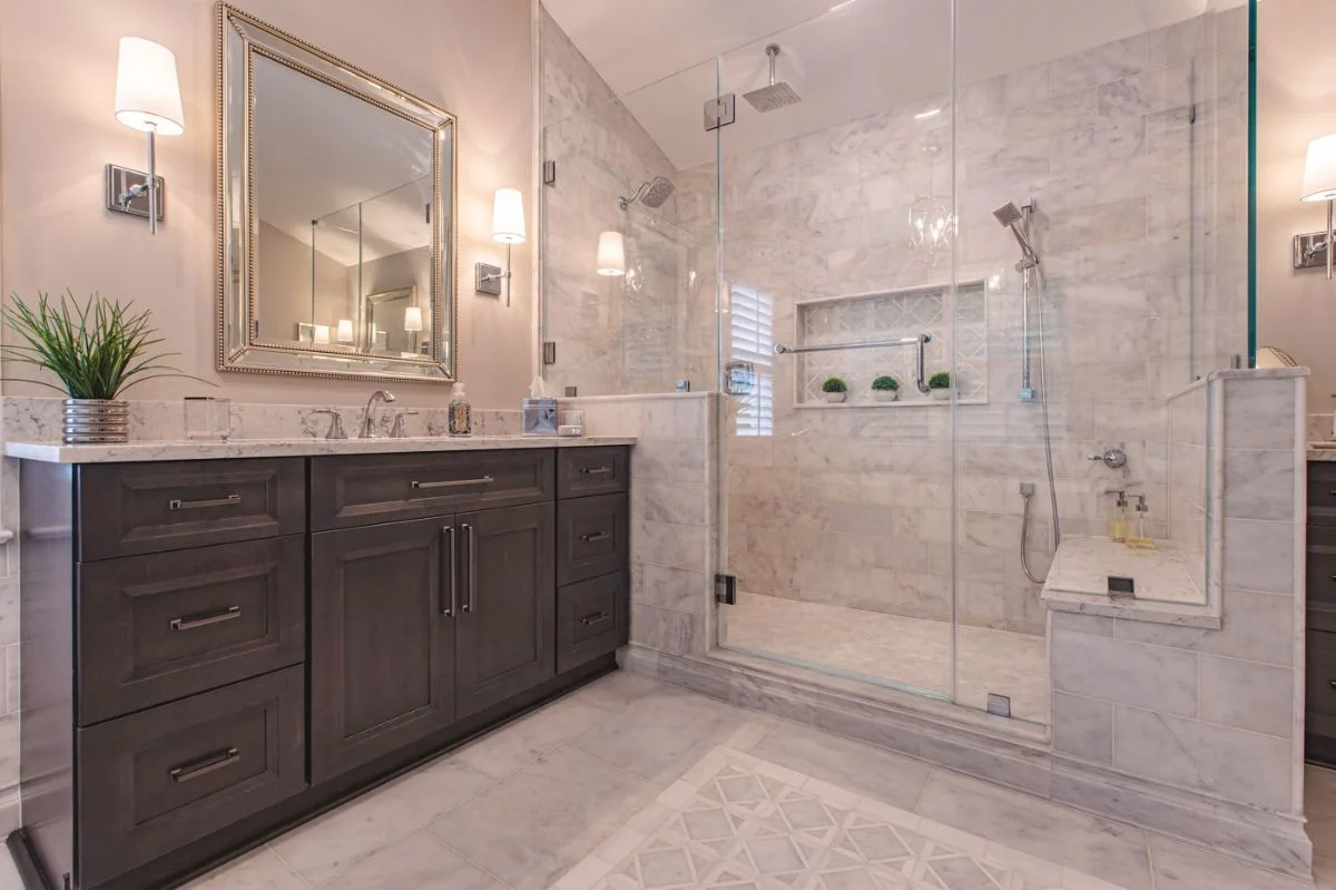 Dark wood vanity and glass-enclosed marble walk-in shower in an Ashburn VA master bathroom remodel.