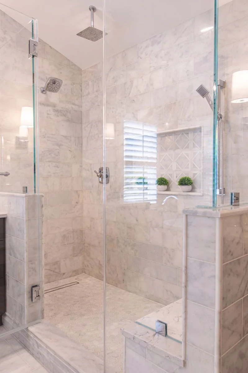 Vertical view of marble walk-in shower with rainfall head, bench, and mosaic niche in Ashburn VA.
