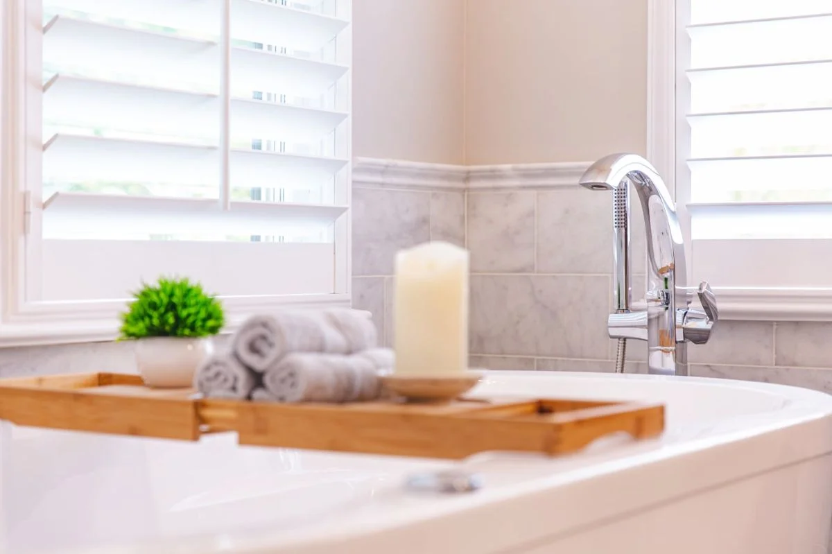 Chrome tub filler faucet and wooden caddy on freestanding tub in an Ashburn VA bathroom.