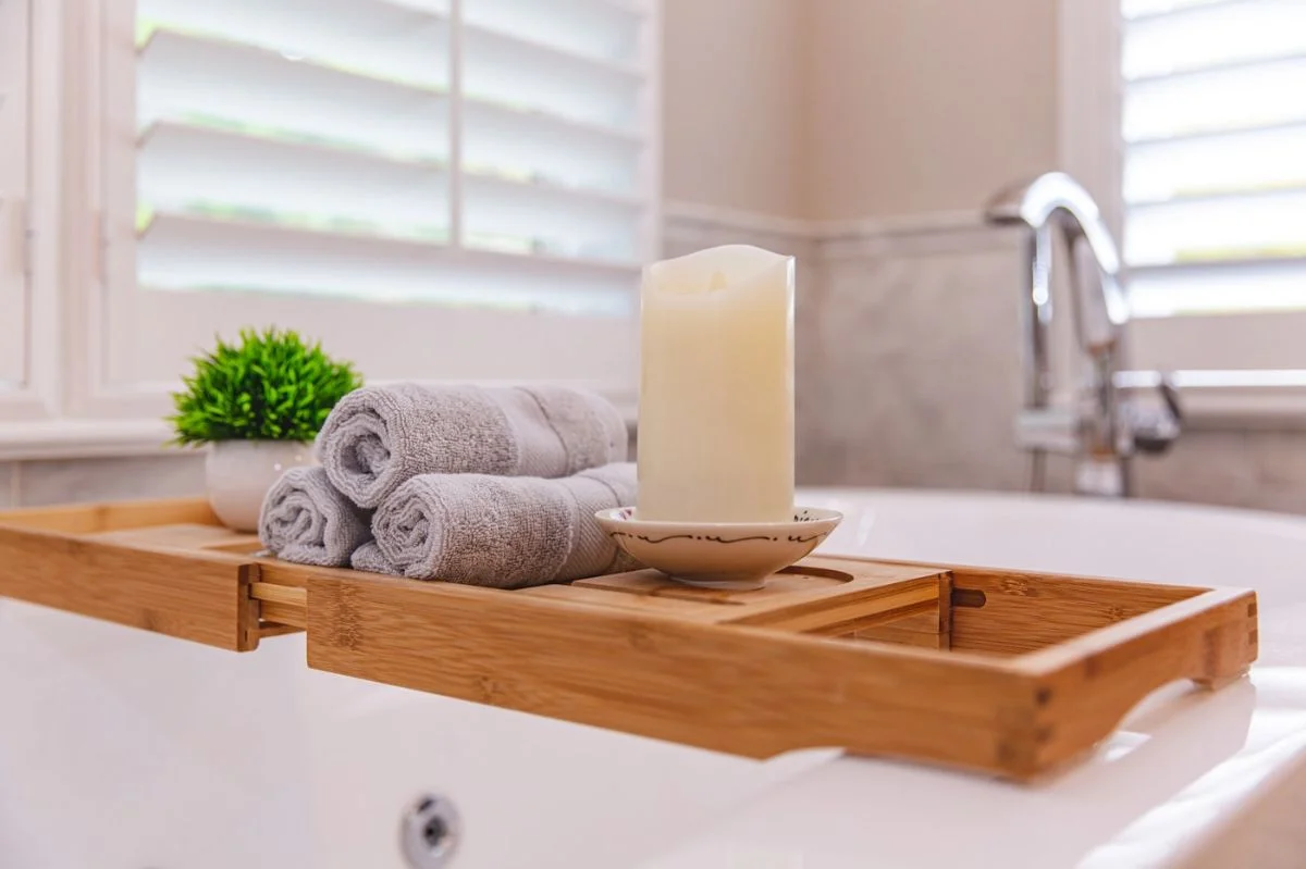 Wooden bathtub caddy with towels and candle on a freestanding tub in an Ashburn VA bathroom.
