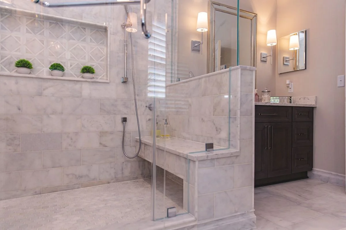 Marble walk-in shower with built-in bench and geometric mosaic niche in an Ashburn VA bathroom remodel.