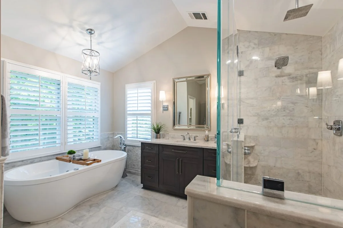Master bathroom in Ashburn VA with freestanding tub, dark wood vanity, and glass walk-in shower enclosure.