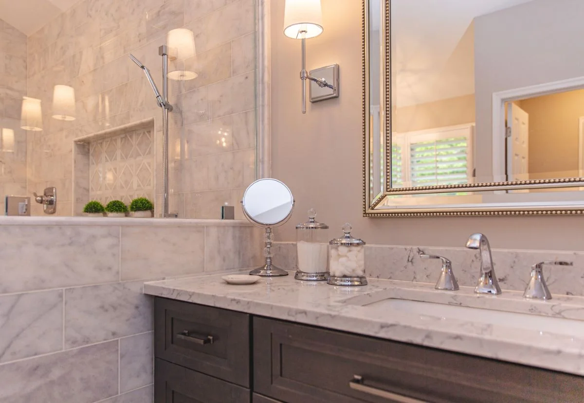 Close-up of dark wood vanity with white marble countertop and chrome faucet in an Ashburn VA bathroom remodel.