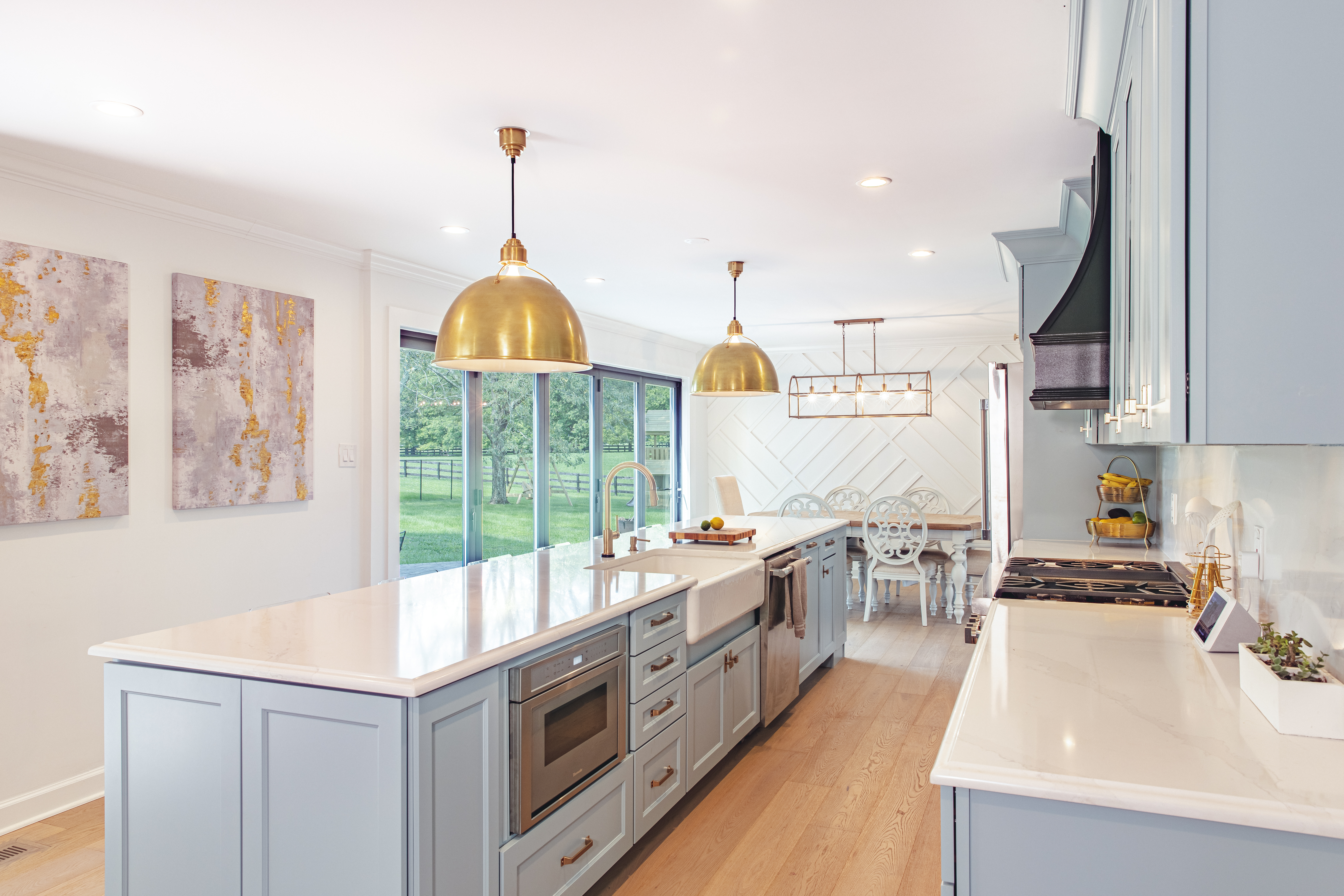 Soft blue kitchen cabinets with a light backsplash and warm metal hardware