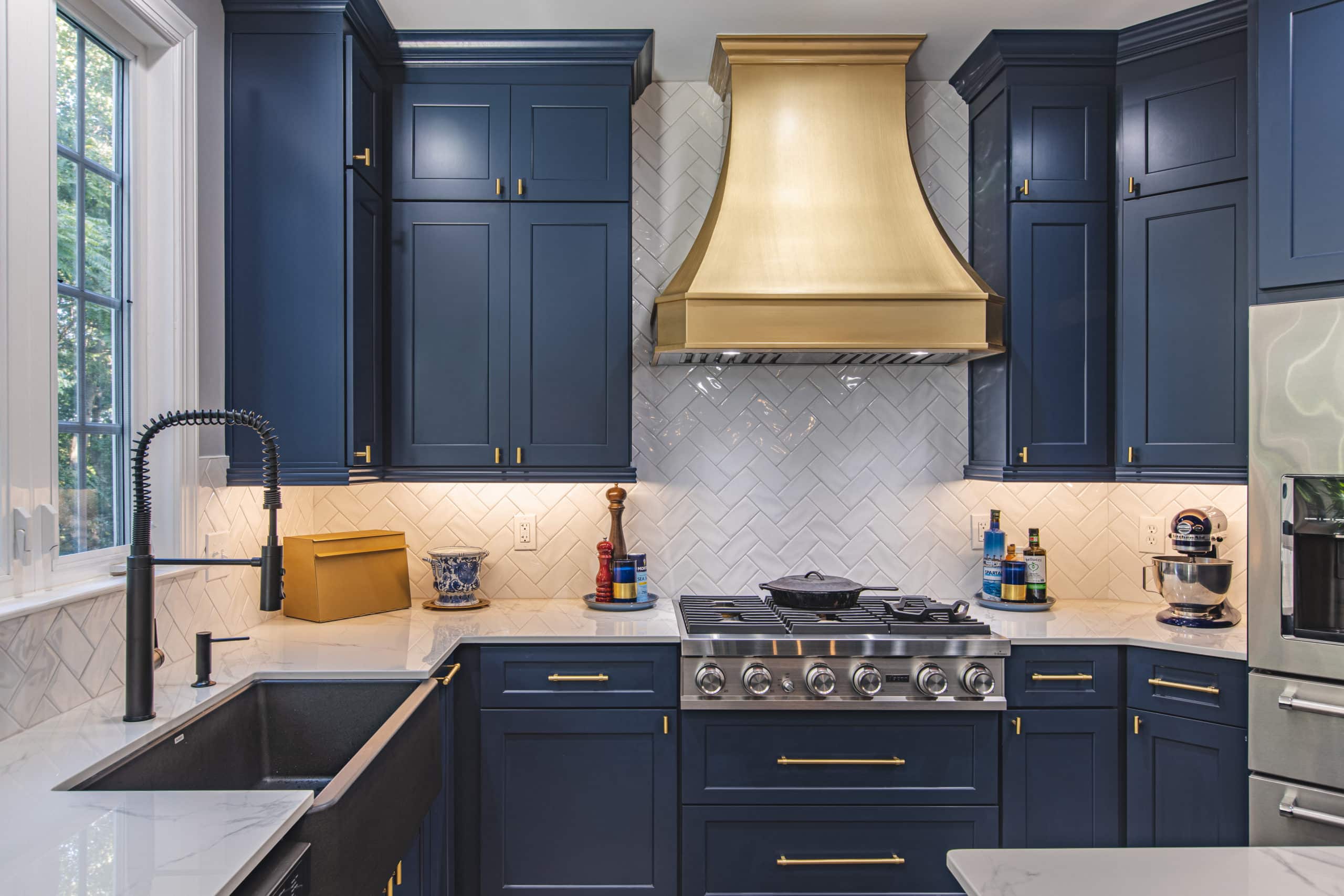 A kitchen with blue cabinets and a gold hood