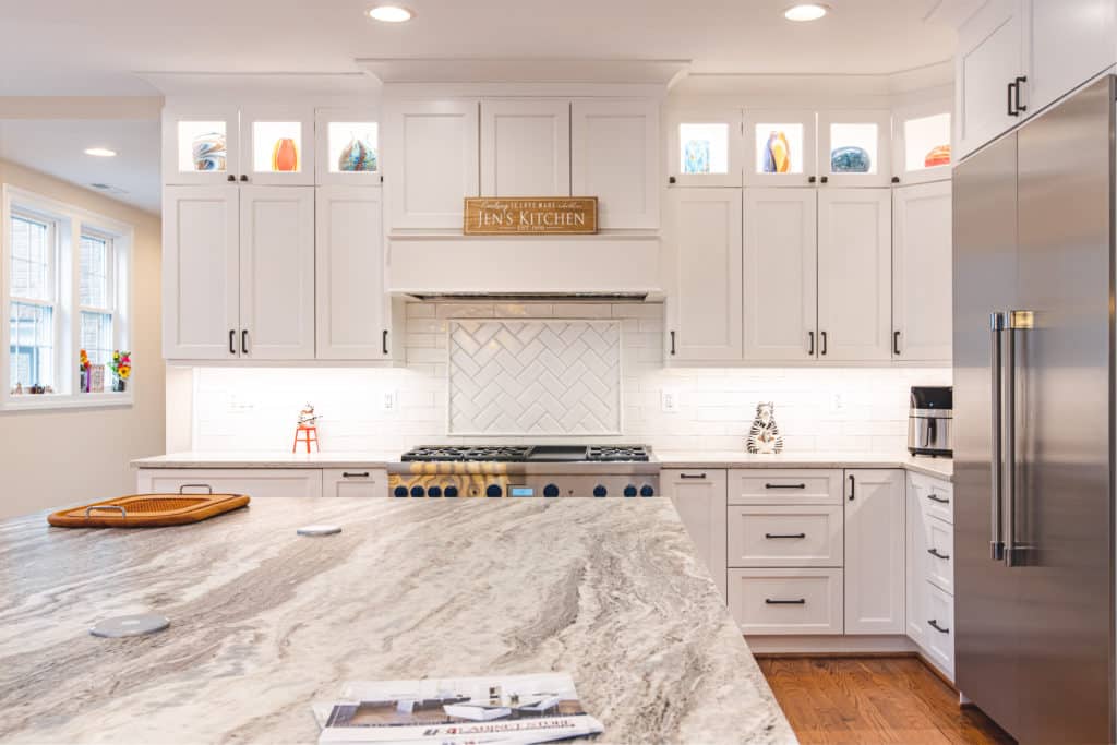 A modern kitchen with sleek white cabinets and a luxurious marble counter top