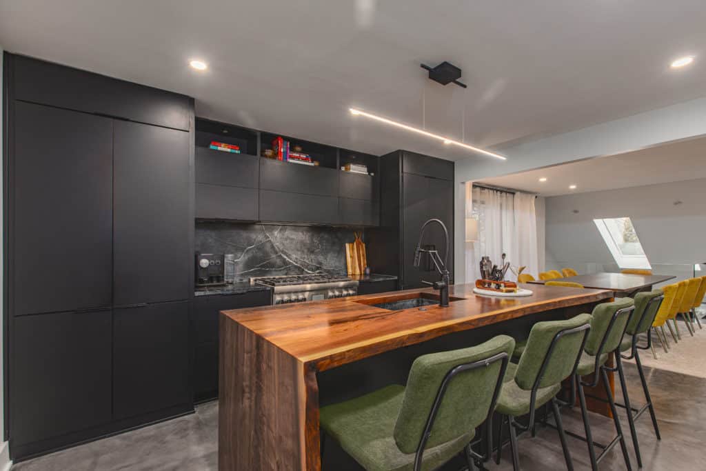 A contemporary kitchen featuring sleek black cabinets and vibrant green chairs