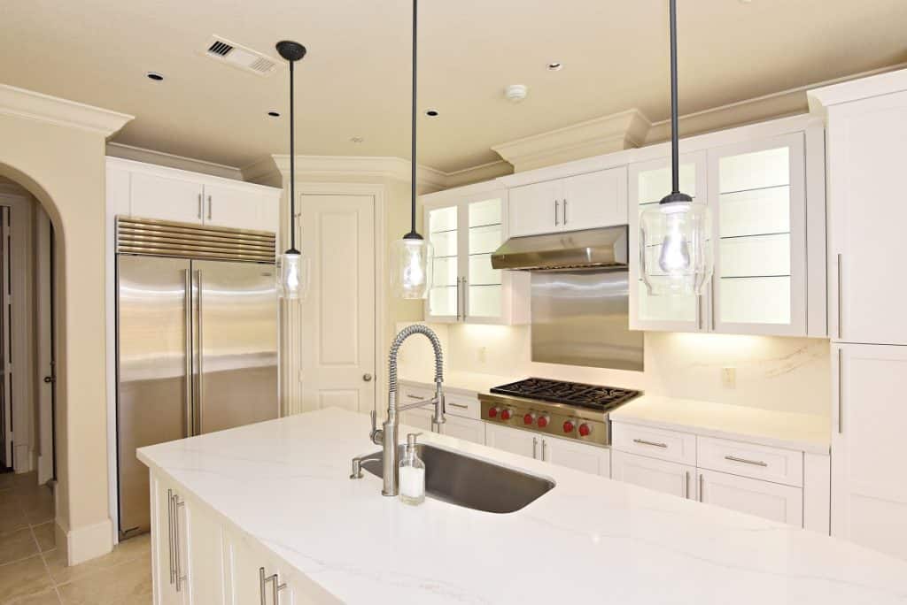 White Kitchen Remodeling Project in Houston, TX 37 A bright kitchen interior with a sink, stove, and refrigerator, illustrating a practical