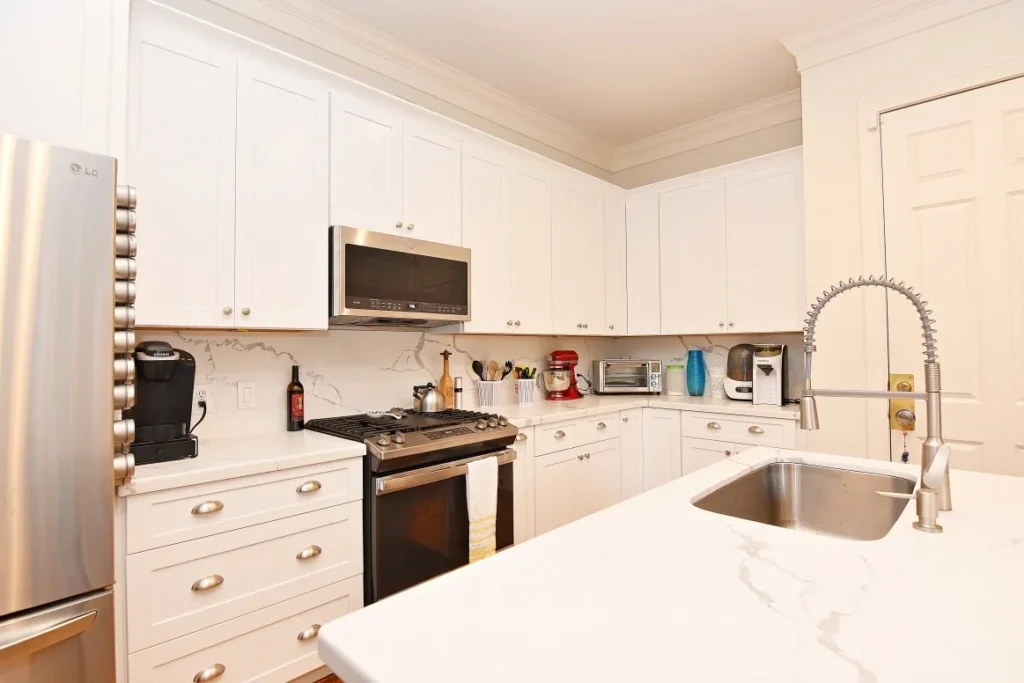 Integrated stainless steel microwave and white cabinetry in a classic Houston kitchen design.
