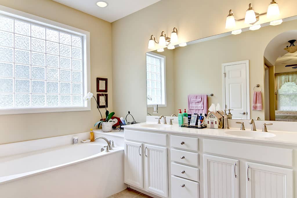 White bathroom cabinets with a tub and a mirror