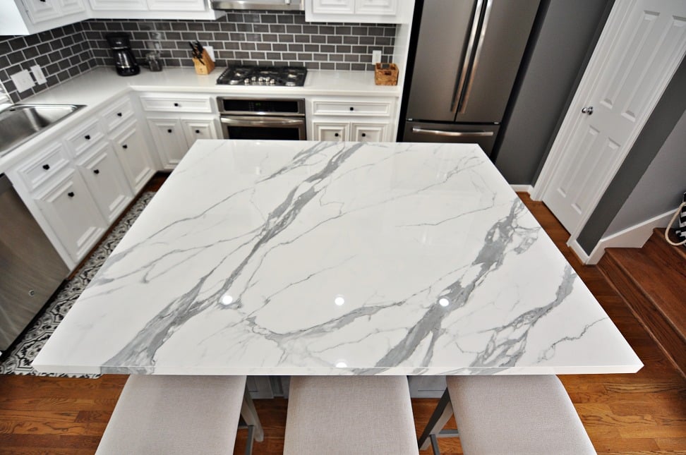 A modern kitchen with sleek marble counter tops and stylish stool for seating