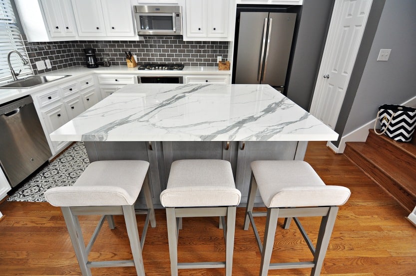 A modern kitchen with sleek marble counter tops and stylish stools for seating