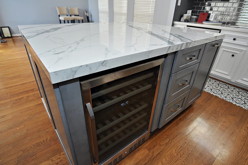 A kitchen island with a wine cooler on it