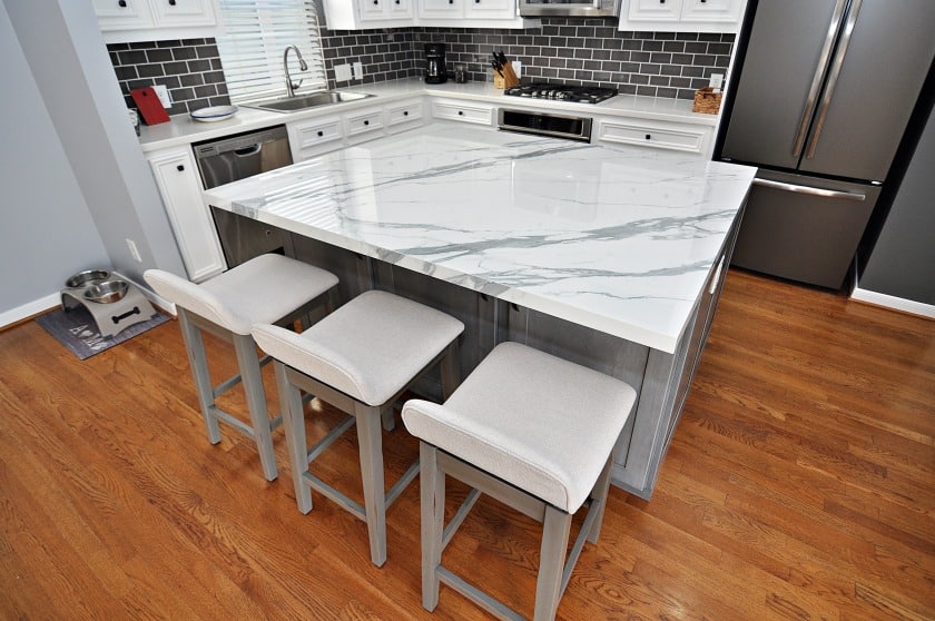A kitchen with white marble counters and bar stools