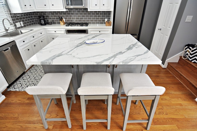 a kitchen with a marble island and white kitchen cabinet