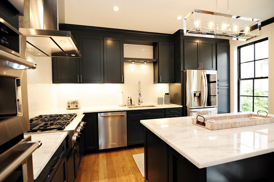 An elegant kitchen showcasing black cabinets and a stunning marble counter top