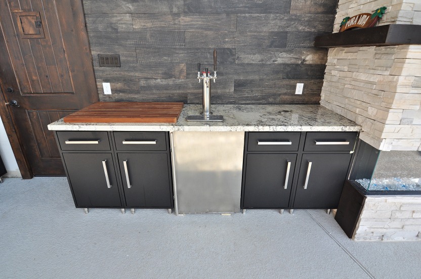Outdoor kitchen with dark cabinets and a sink