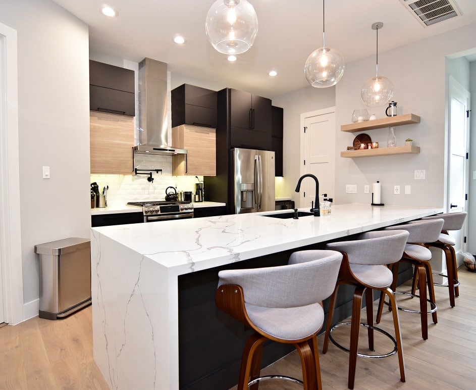 A kitchen with a sleek white countertops and elegant black cabinet