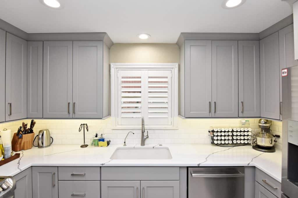 A kitchen with sleek gray cabinets and white marble countertops