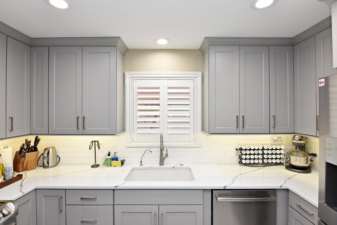 A kitchen with sleek gray cabinets and white marble countertops