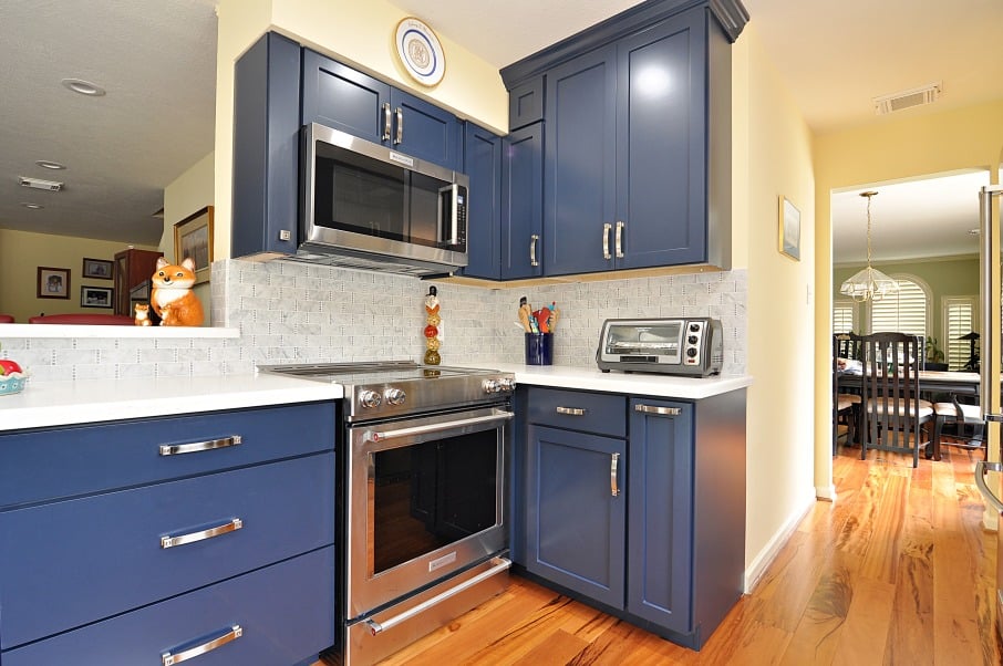 a kitchen with blue cabinets and a stainless steel stove