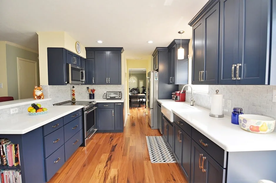Symmetrical galley kitchen with parallel counters, navy cabinets, white quartz countertops, and clear center walkway