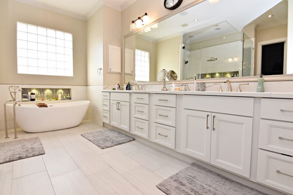 White bathroom cabinets with a large tub and a large mirror