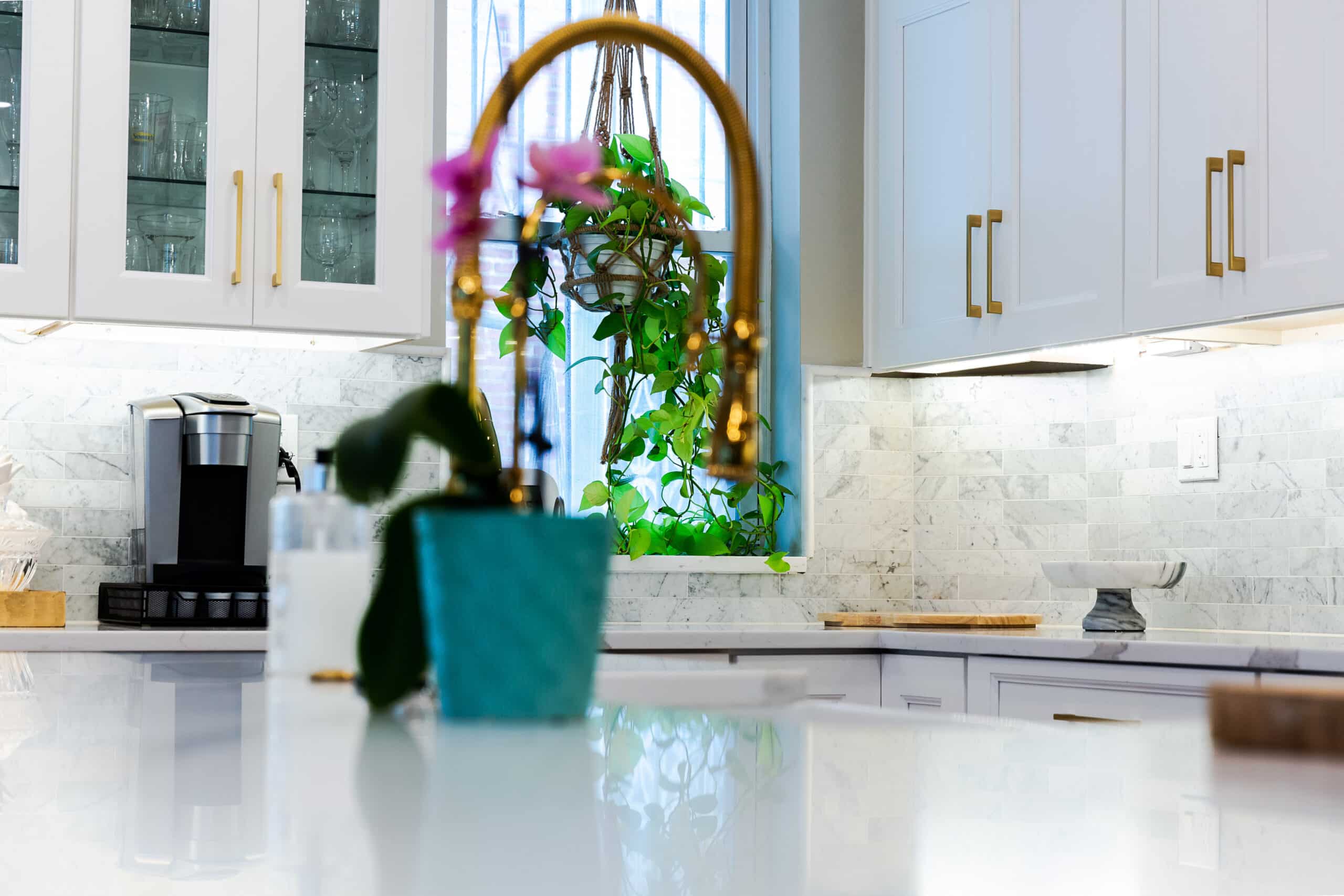 A kitchen with white cabinets and gold fixtures