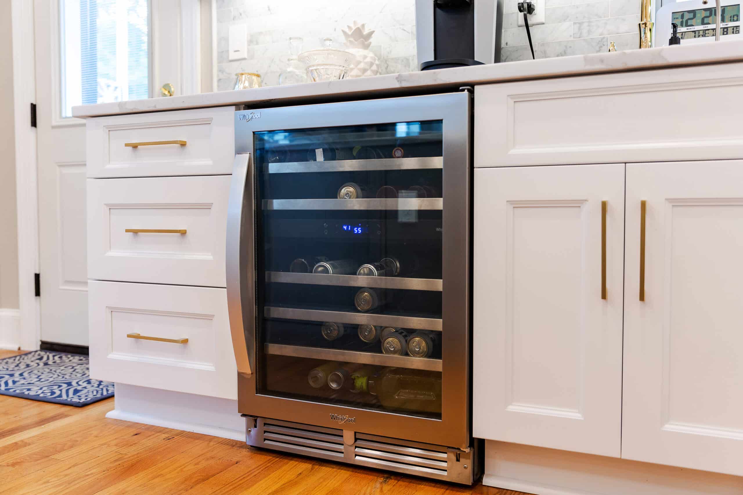 A wine cooler in a kitchen with white cabinets
