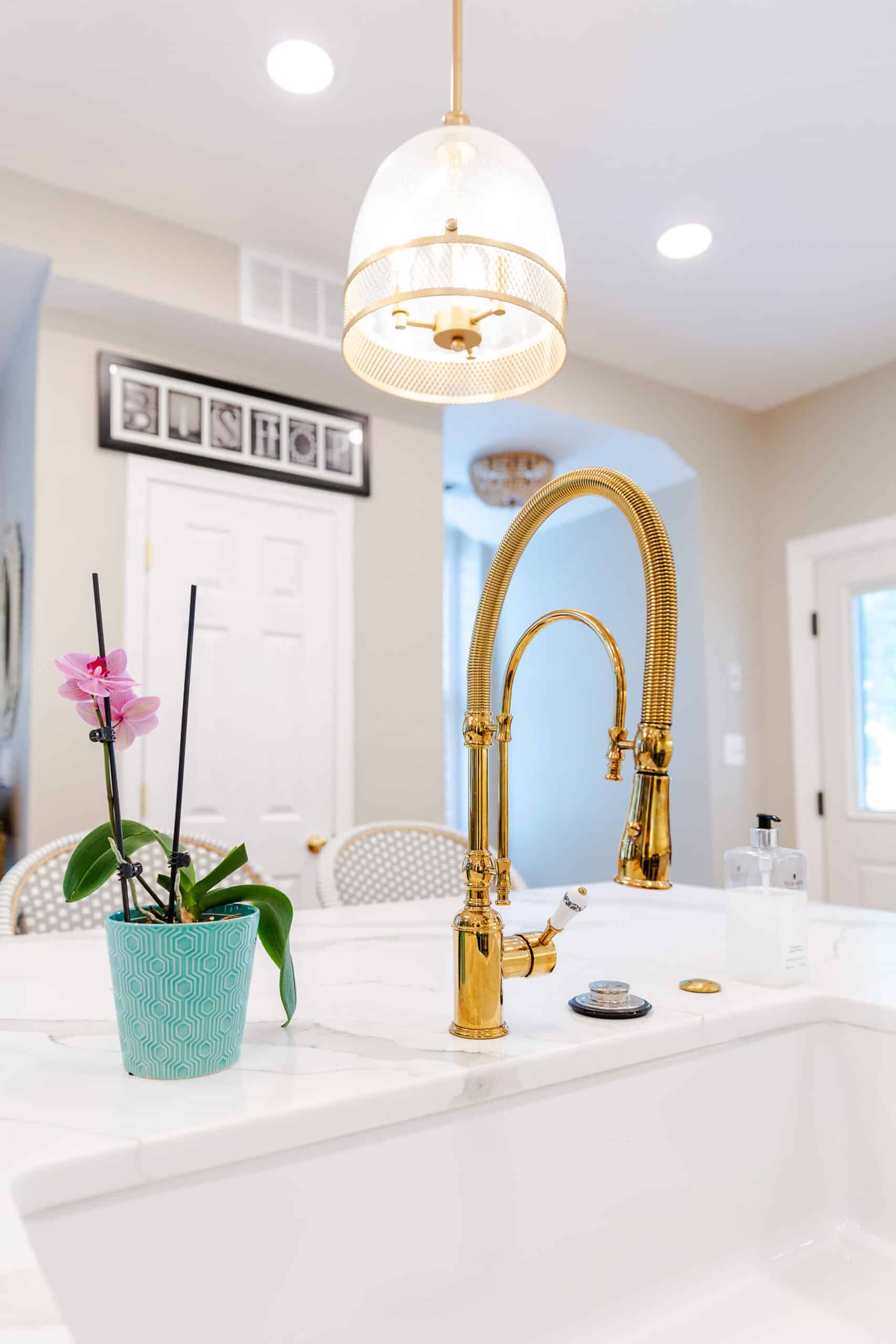 A stylish kitchen sink with a gold faucet and a potted plant