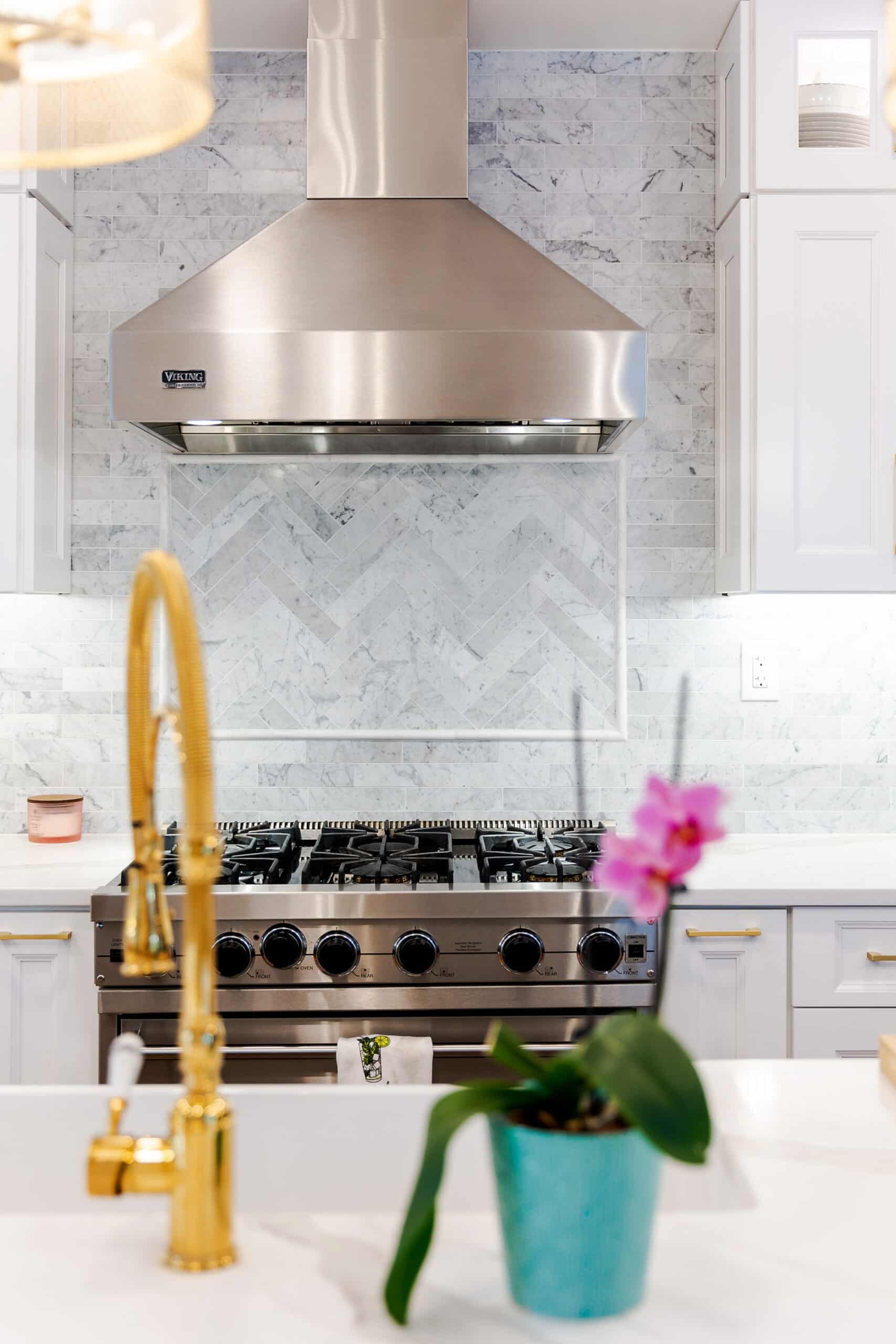 A kitchen with white cabinets and a range hood