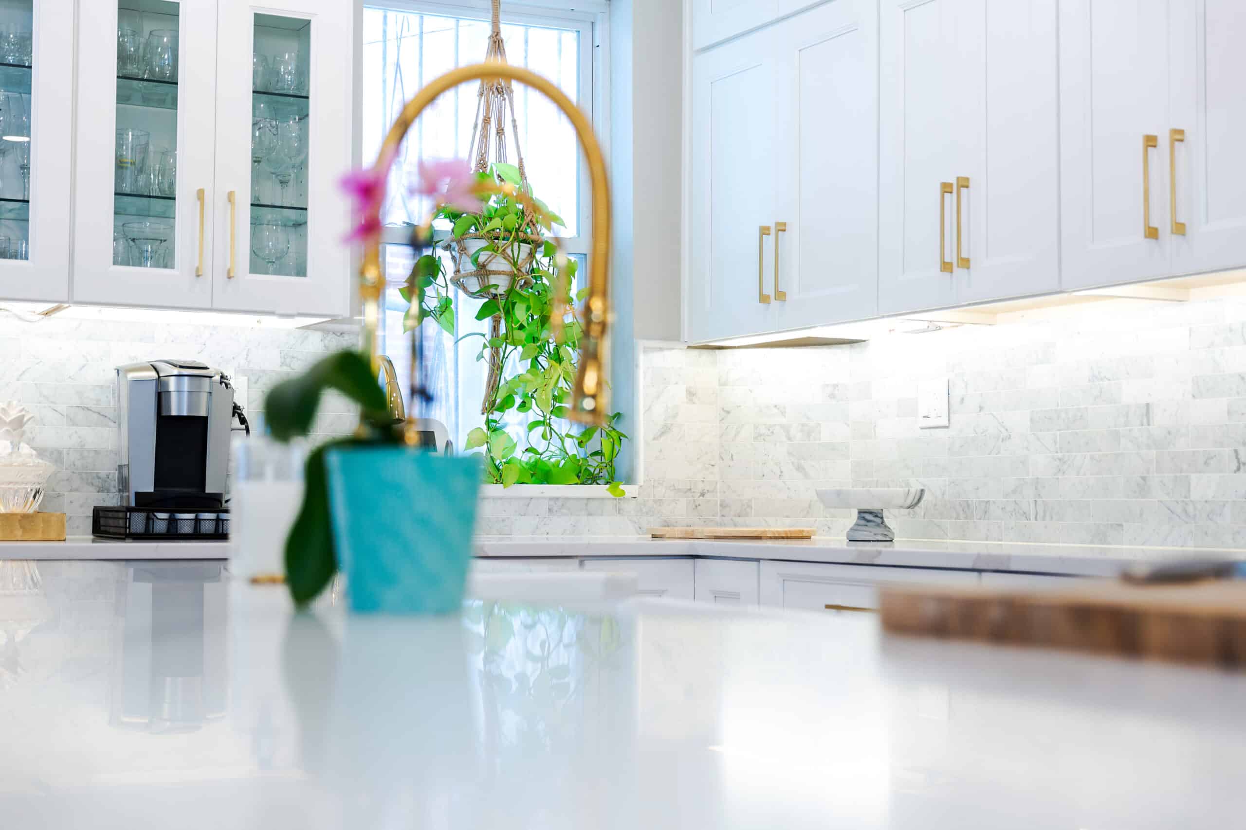A kitchen with white cabinets and a gold faucet