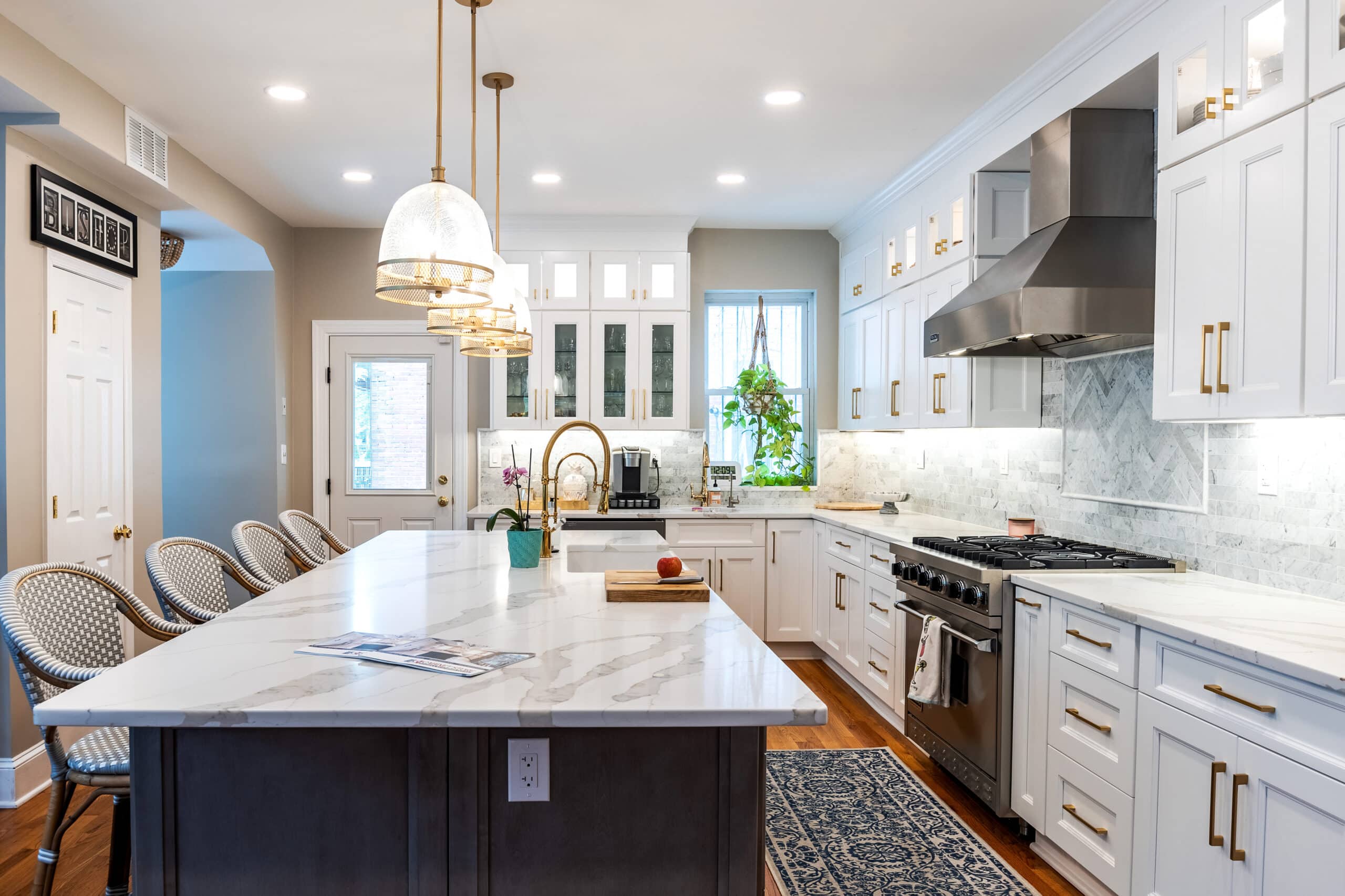 A kitchen with white cabinets and a white marble island