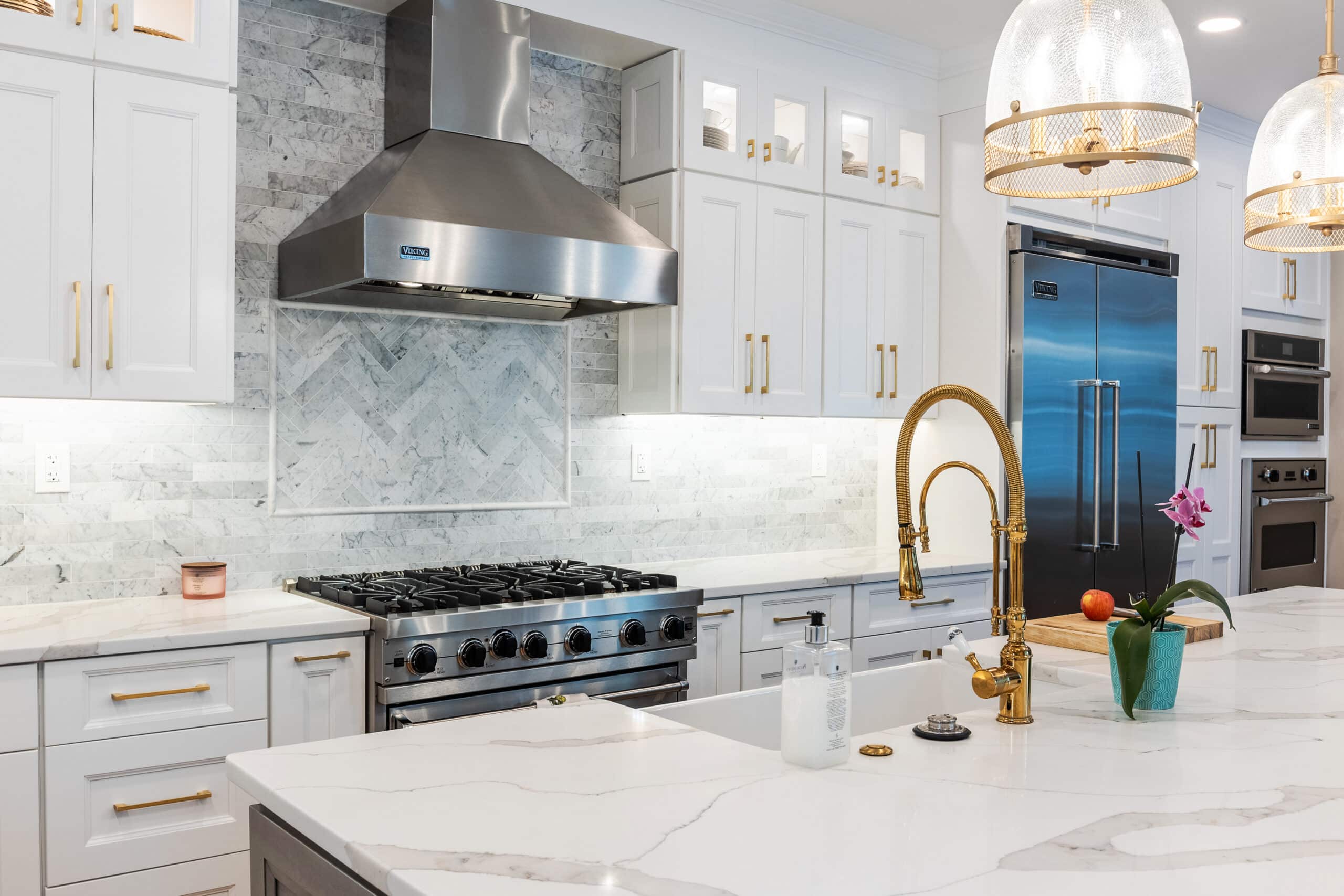 A kitchen with white cabinets and brass fixture