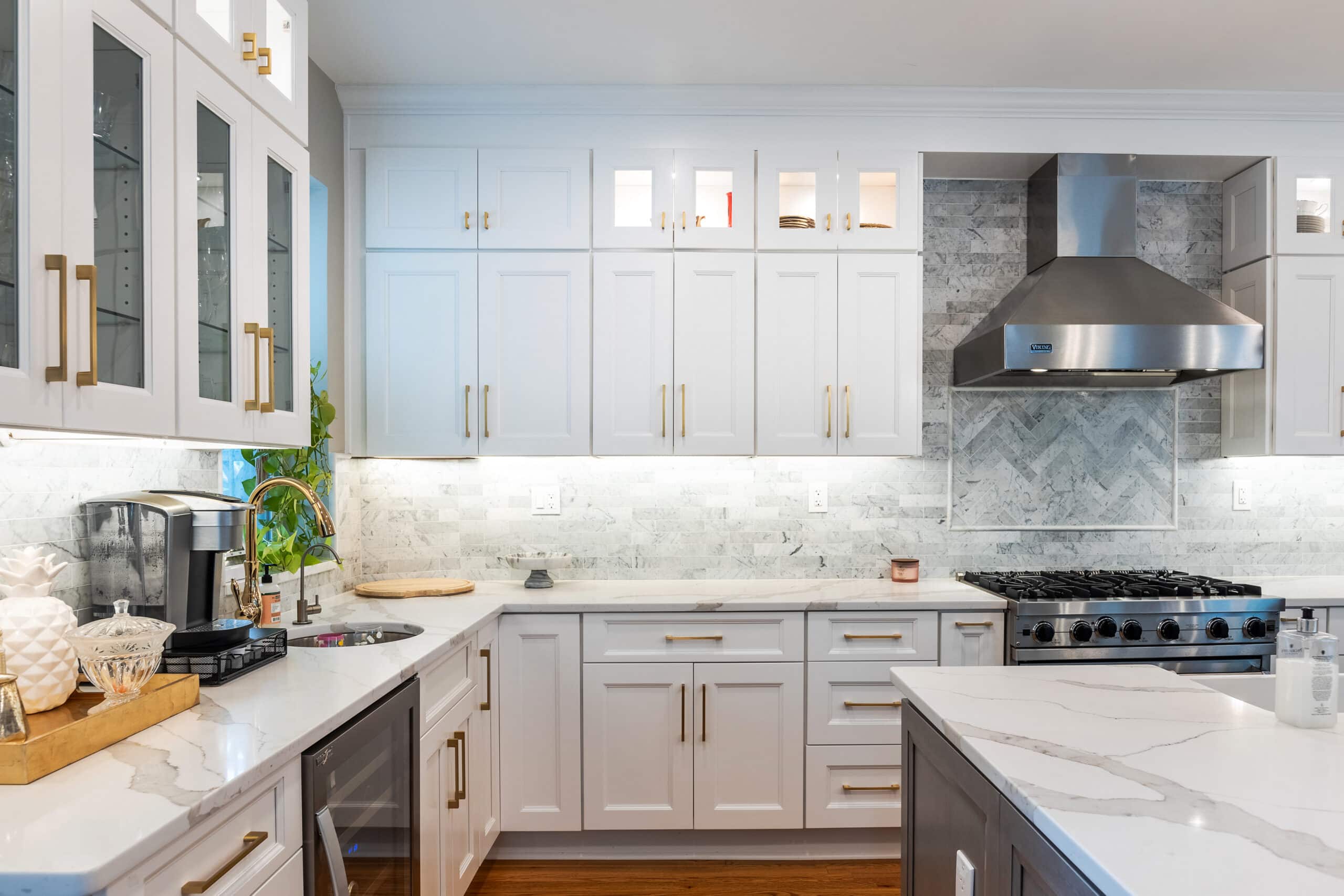 A kitchen with white cabinets and marble countertops