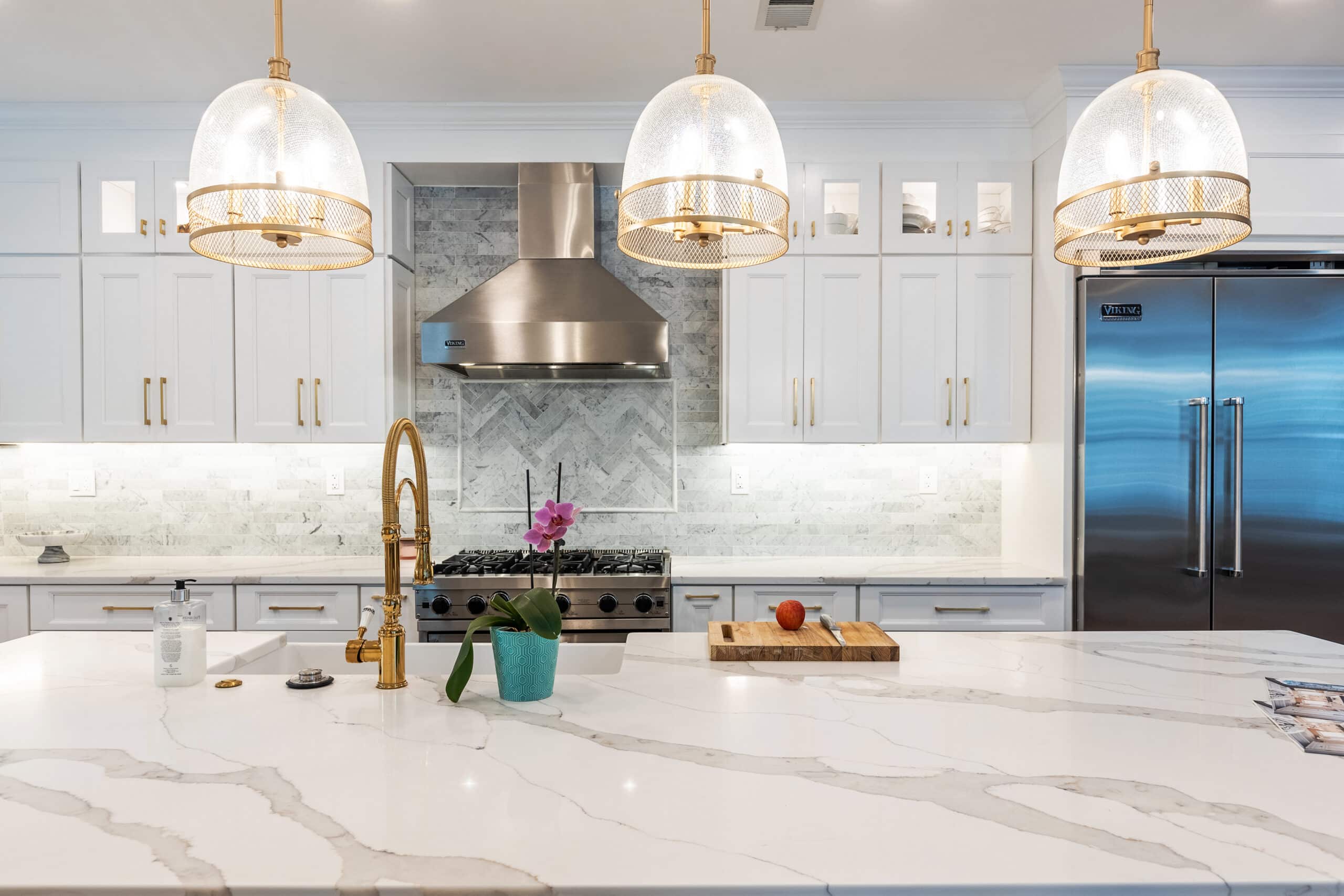 A kitchen with elegant marble counter tops and sleek white cabinets