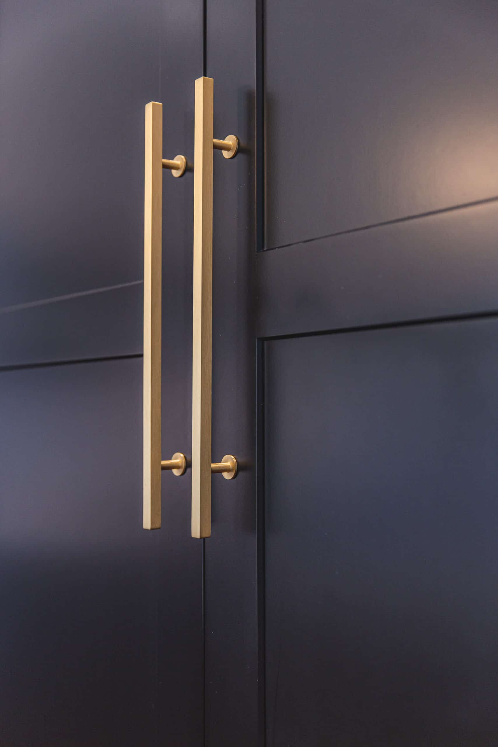 A close-up of a black cabinet with brass handles