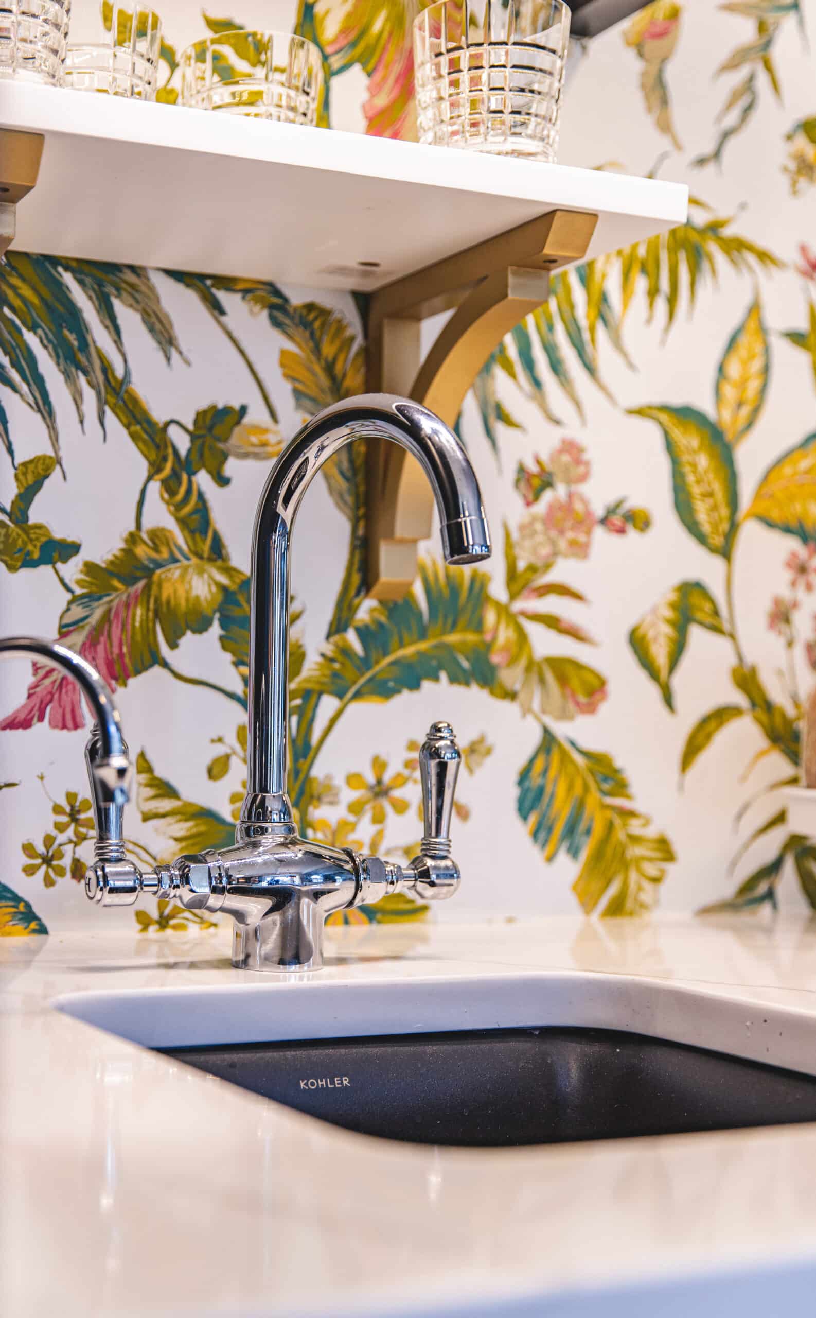 A kitchen sink with vibrant tropical wallpaper