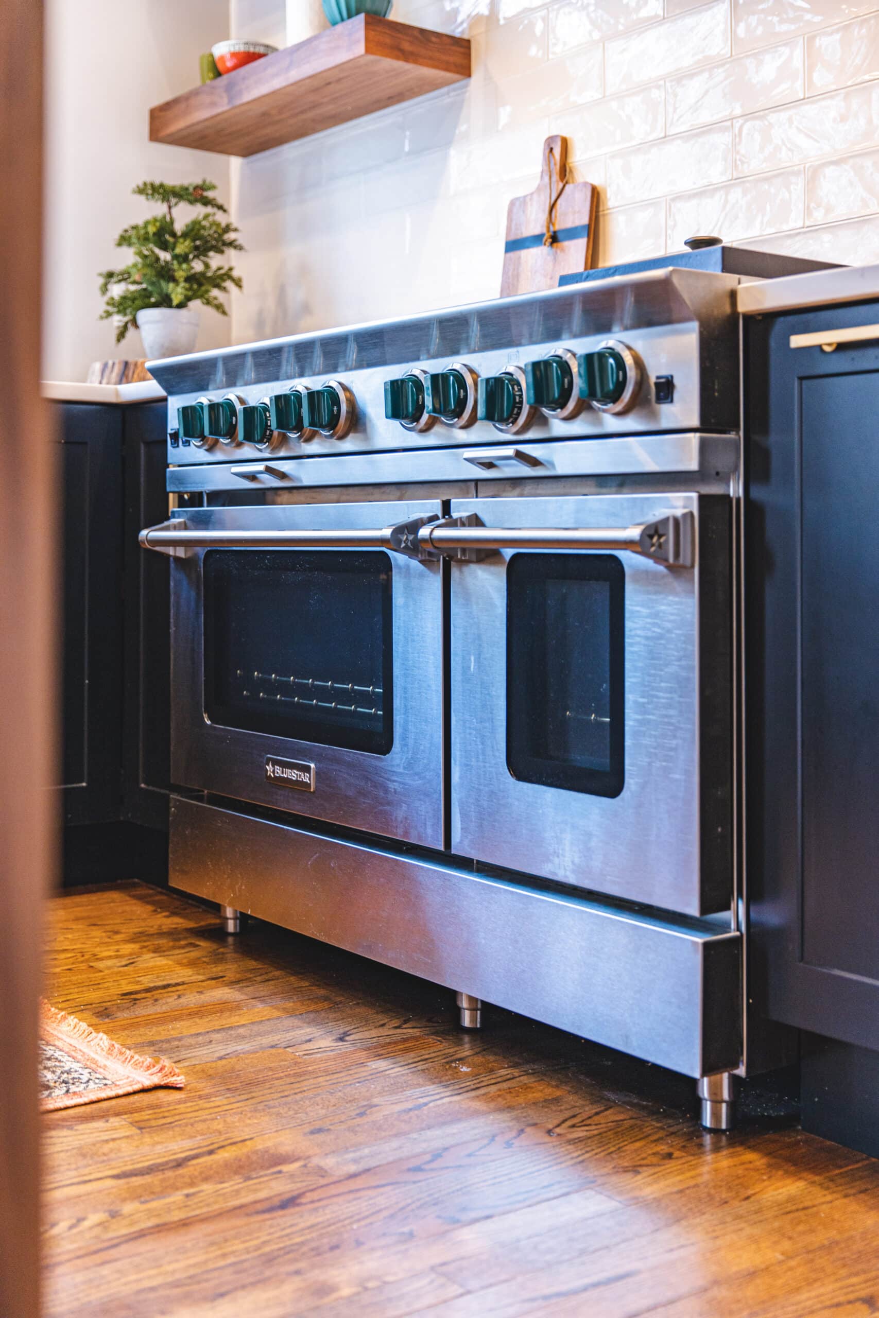A stainless steel oven in a kitchen with wood floors.