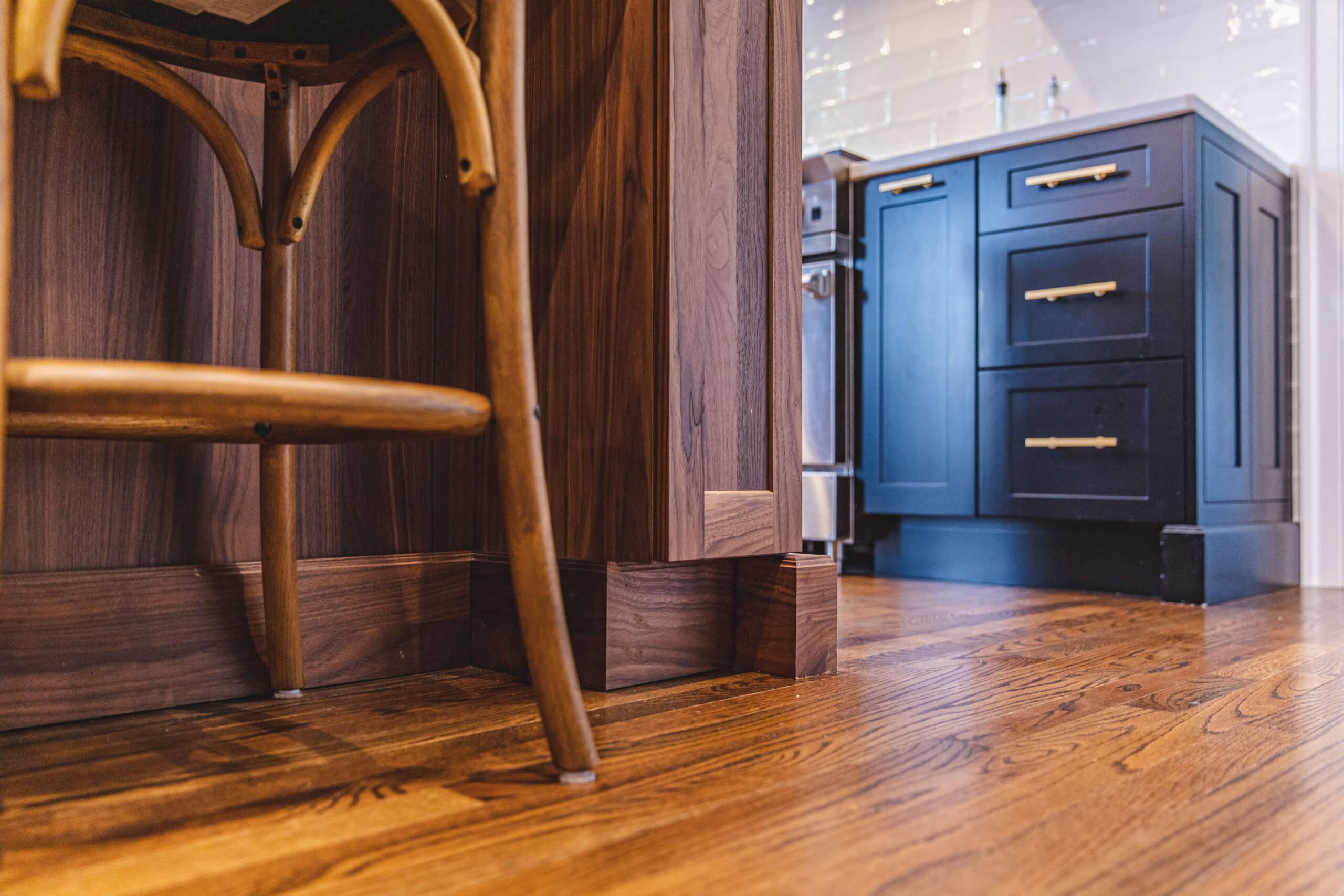 A kitchen with a wooden floor and a bar stool.