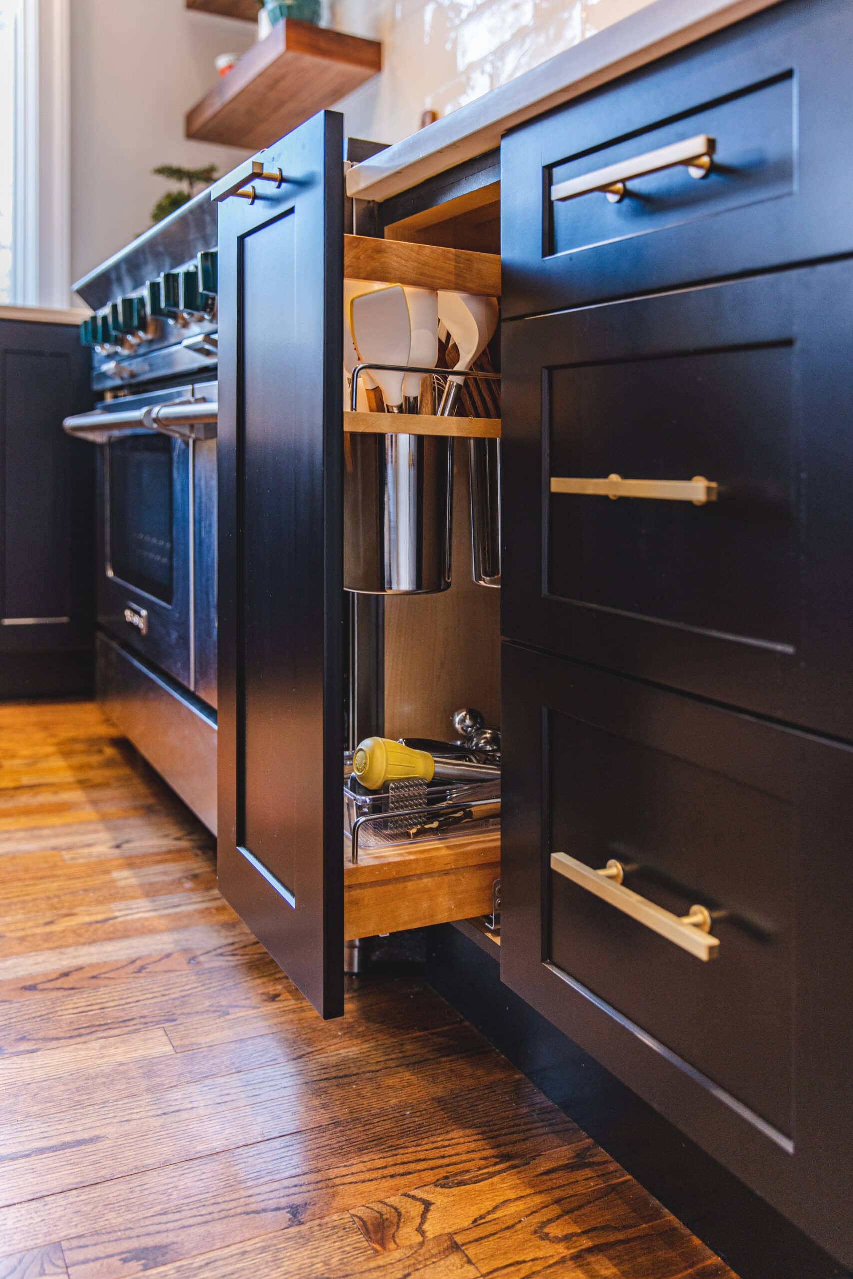 A kitchen with sleek black cabinets and warm wooden floors