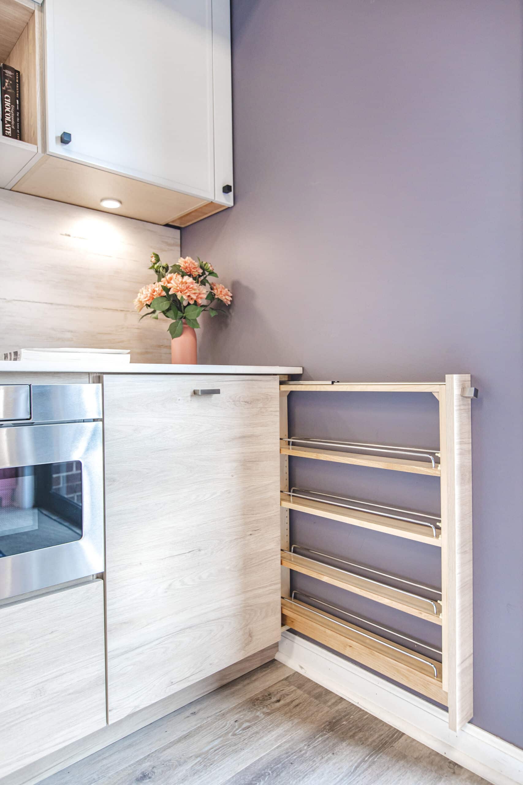A kitchen with a wooden shelf and a purple wall
