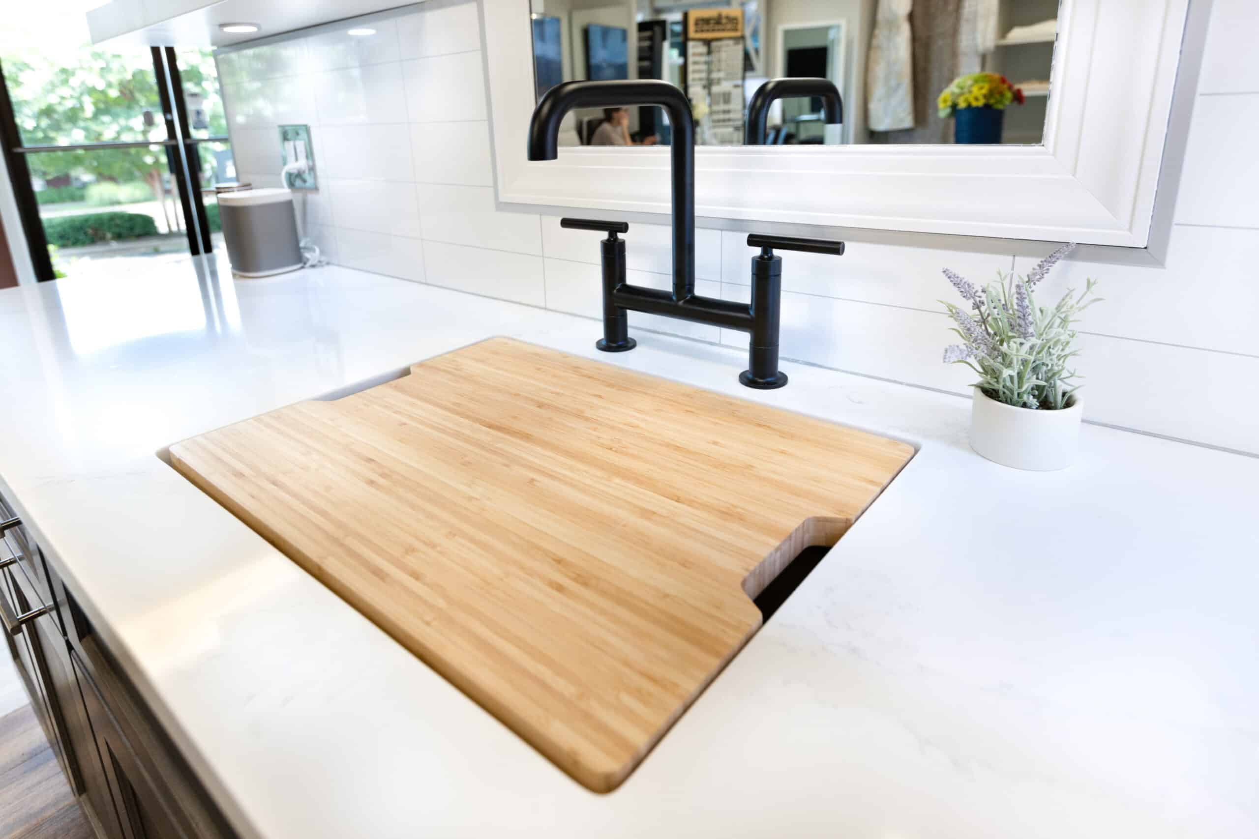 A kitchen sink with a wooden cutting board on it