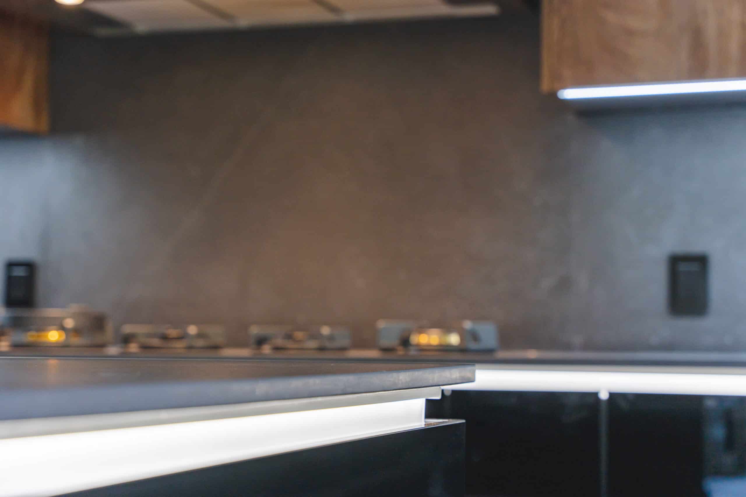 A kitchen with a sleek black counter top and a bright light illuminating the space