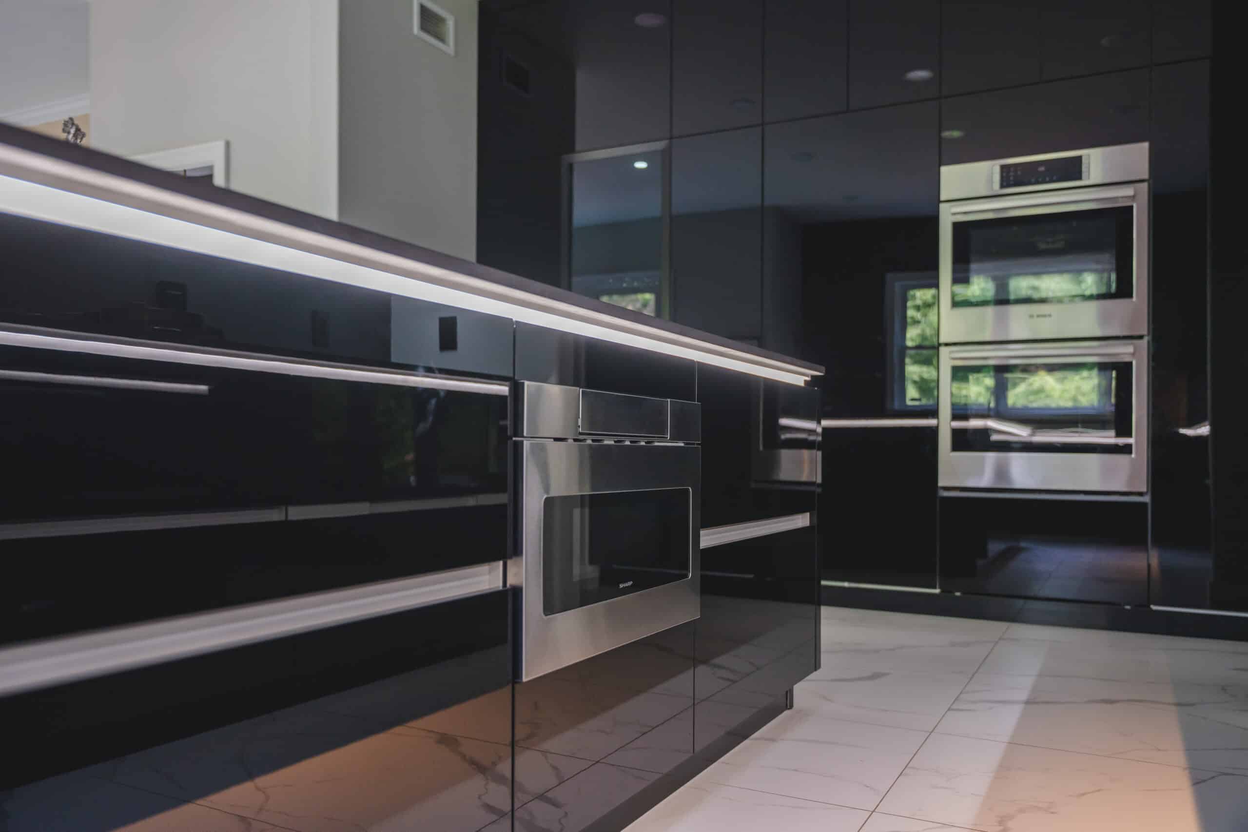 A contemporary kitchen featuring sleek black cabinets and stainless steel appliances